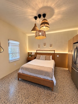 Une chambre à coucher comprenant un lit, des tables de chevet, une armoire et un réfrigérateur encastré.
