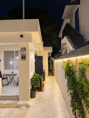 Una casa moderna con un área de estar cubierta al aire libre, una escalera y un muro de jardín.