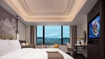 A modern hotel room with a large bed, a desk, a TV, and a city view.