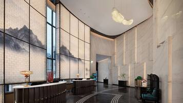 A spacious lobby with a reception desk, seating area, and a large window offering a view of the cityscape.