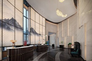 A spacious lobby with a reception desk, seating area, and a large window offering a view of the cityscape.