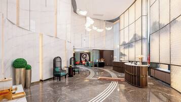 A modern lobby with a marble floor, reception desk, seating area, and large windows.