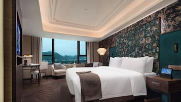 A hotel room with a large bed, a desk, and a view of mountains.