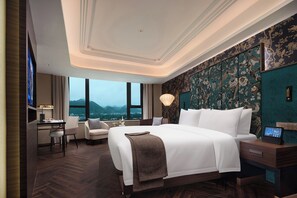 A hotel room with a large bed, a desk, and a view of mountains.
