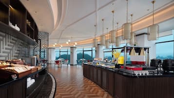 A modern hotel lobby with a central bar area, seating arrangements, and large windows offering a view of the mountains.