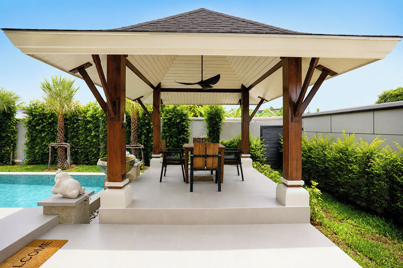 A covered outdoor seating area with a pool, wooden furniture, and a pergola structure.