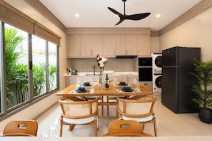 A modern kitchen with a dining table set for four, a ceiling fan, and a black refrigerator.