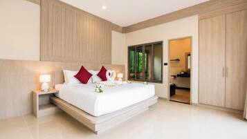 A modern hotel bedroom with a large bed, wooden headboard, bedside lamps, and a view of the bathroom.