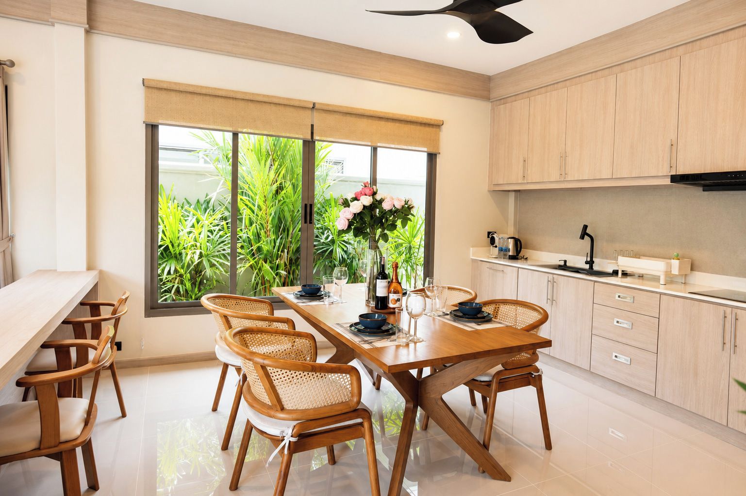 A modern kitchen with a dining area, large windows, and a view of greenery.