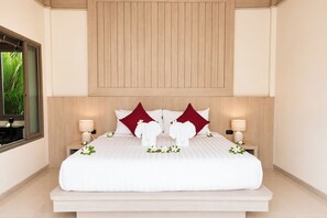 A hotel room with a large bed, two nightstands, a wooden headboard, and a window with a view of greenery. - Secluded New Villa with Private Pool 2 Bedrooms (Tambon Rawai)