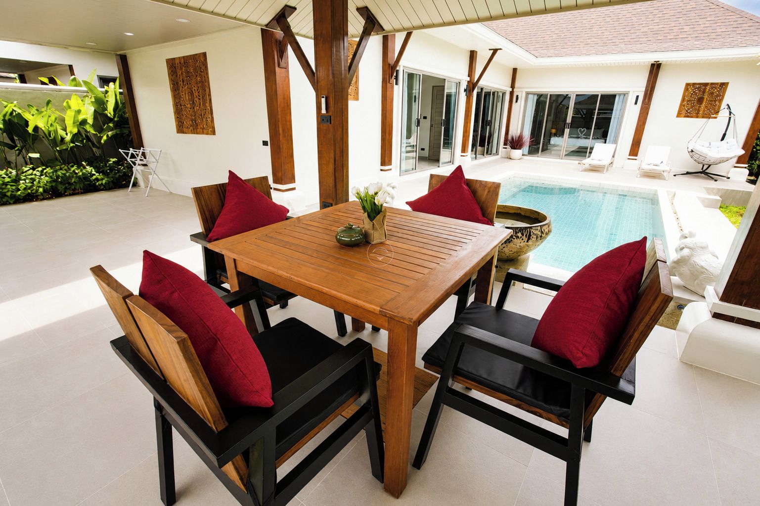A wooden table with chairs, a pool, and a view of the house.