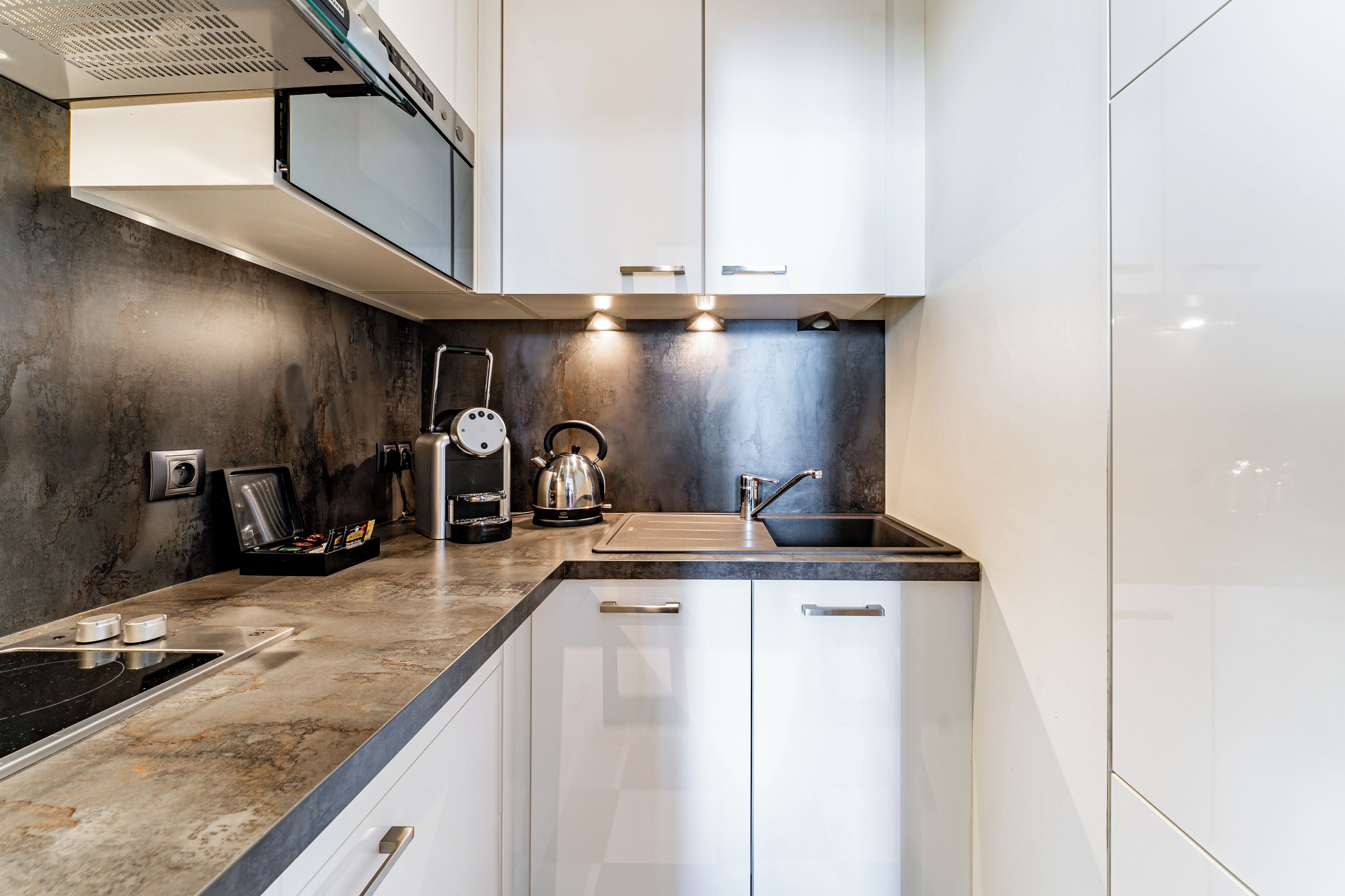 Una cucina moderna con piano cottura integrato, bollitore e lavandino.