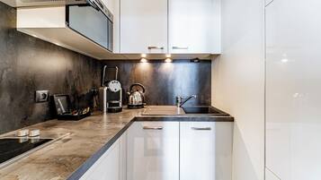 Una cucina moderna con piano cottura integrato, bollitore e lavandino.