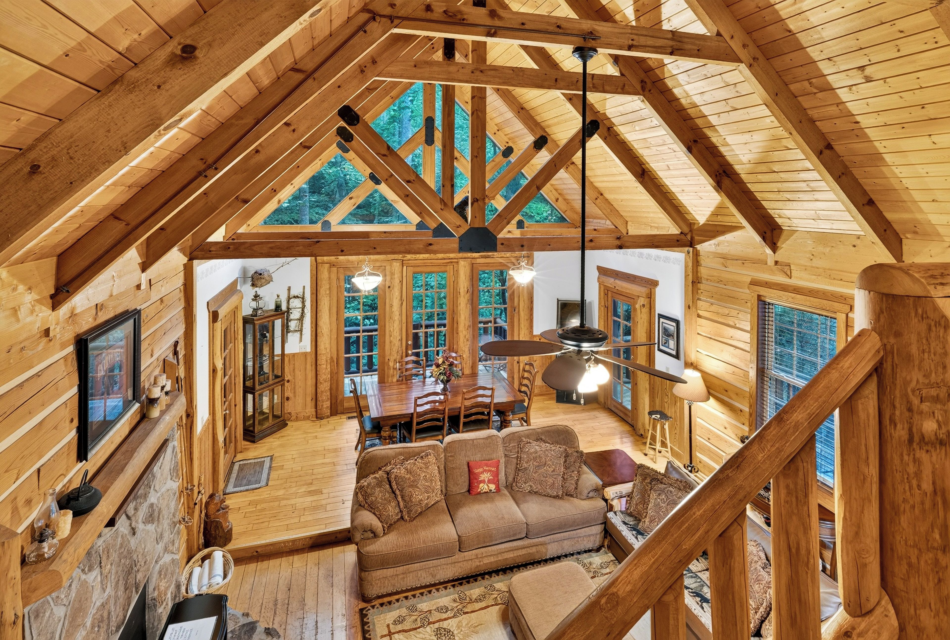 A wooden interior with a high ceiling, a dining area, and a sofa.