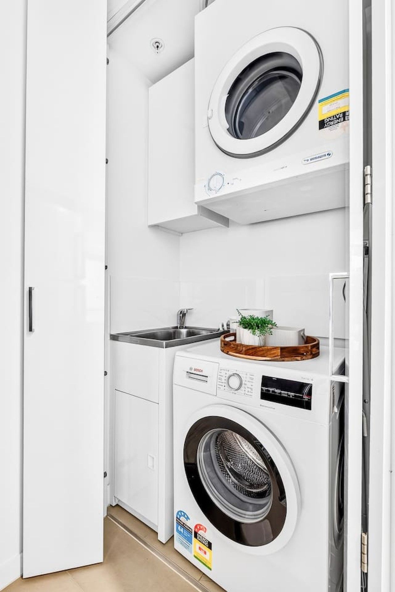 A compact laundry room with a washing machine, a dryer, and a sink.