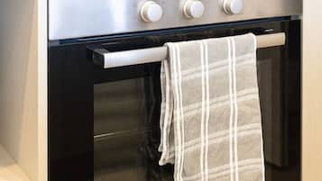 A kitchen with a Bosch oven, a towel hanging on the oven door, and a plant on the countertop.