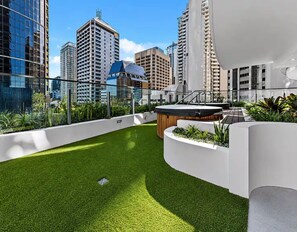 Jardim no terraço com uma piscina pequena, cercado por edifícios modernos.