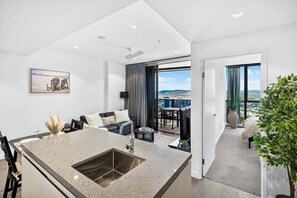 Un appartement moderne doté d’un îlot de cuisine, d’un coin repas et d’un balcon offrant une vue sur la ville.