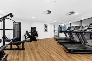A gym with treadmills, weight machines, and a mirror wall. - Luxe 1BR | Queen’s Wharf | Casino & Pool (Brisbane City)