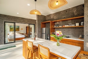 Una cocina moderna con encimera de mármol, sillas de madera y una mesa de comedor.