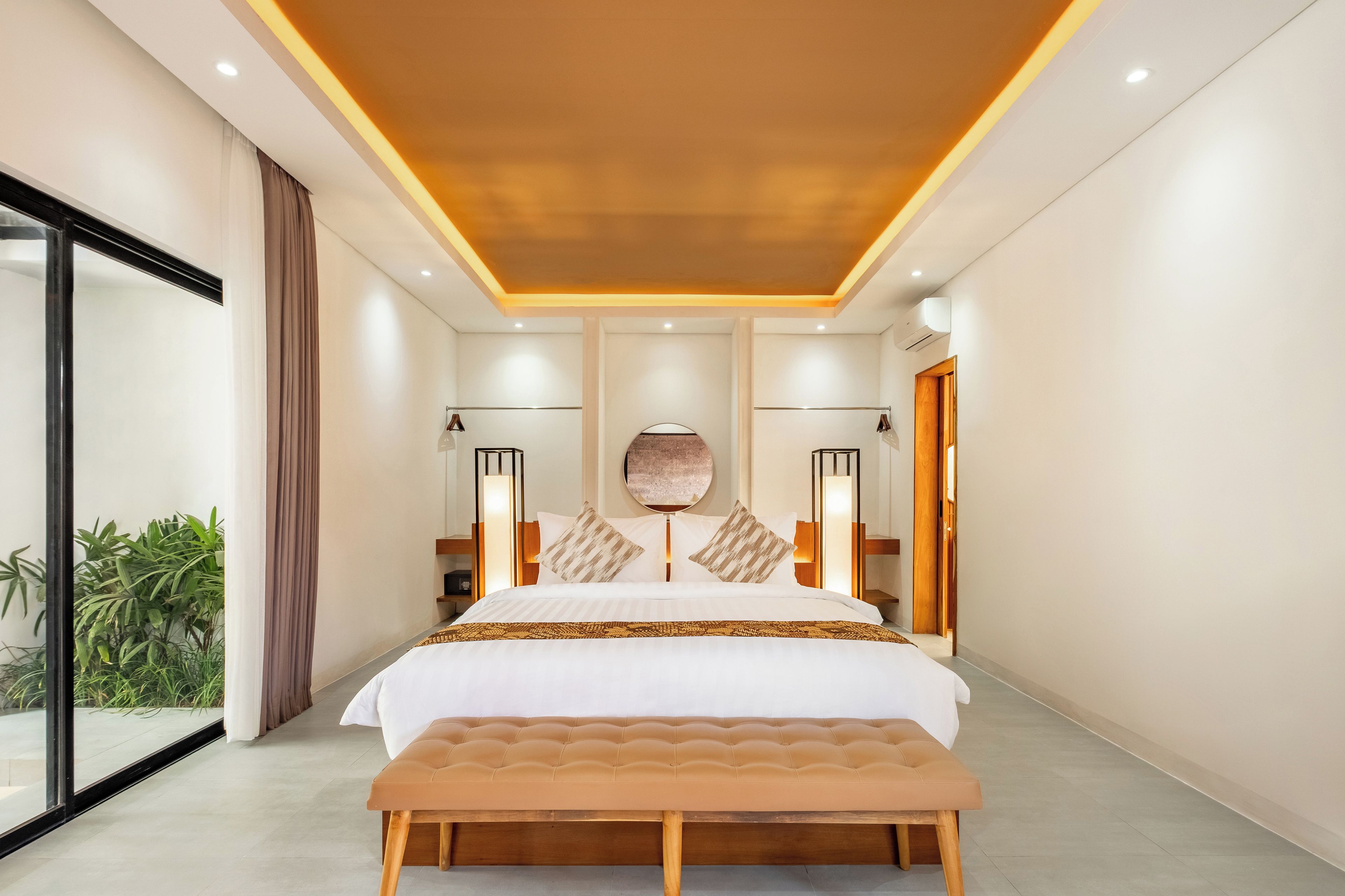 A modern bedroom with a large bed, bedside lamps, and a view of the outdoors.