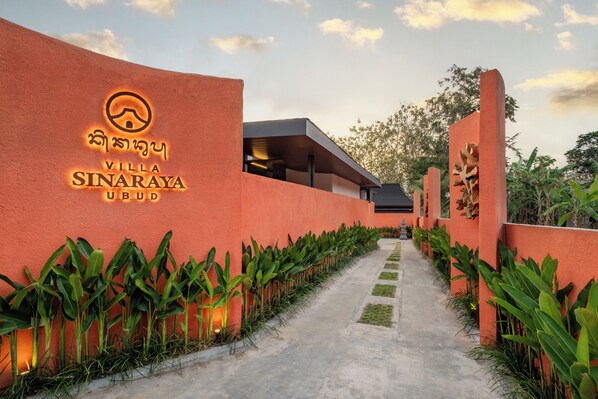 A pathway leading to Villa Sinaraya Ubud with a sign on the wall.
