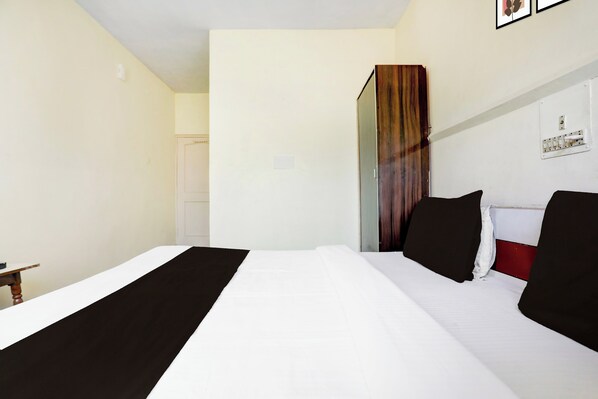 A hotel room with a bed, a nightstand, and a door.