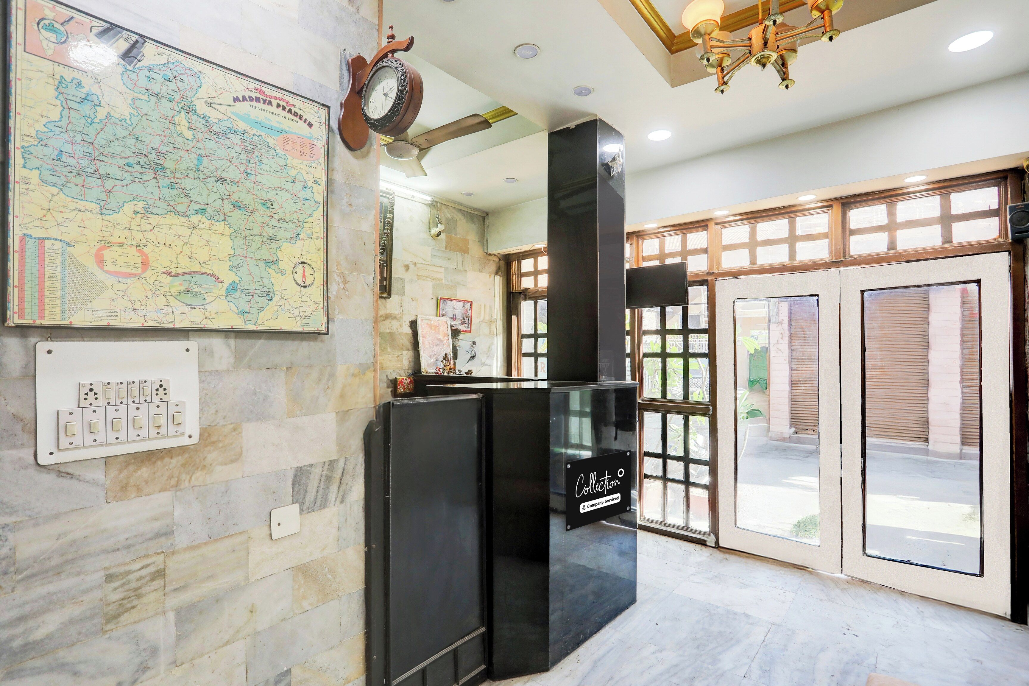 A lobby with a vintage map, a wall-mounted clock, a modern black cabinet, and a large window with a view of the outside.