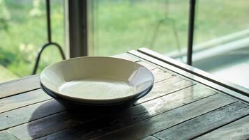 A bowl on a wooden table with a view of greenery through a window.