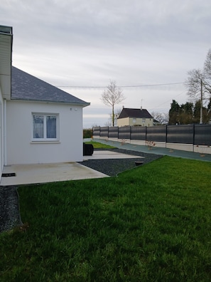 A residential property with a well-maintained lawn, a paved driveway, and a fenced backyard.