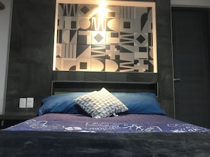 A bedroom with a bed, pillows, and a wall with geometric patterns.