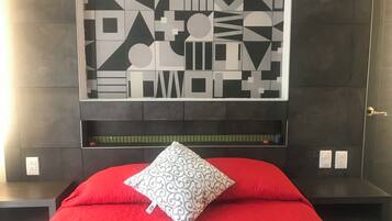 Una stanza con un letto, un'opera d'arte appesa al muro e un comodino.