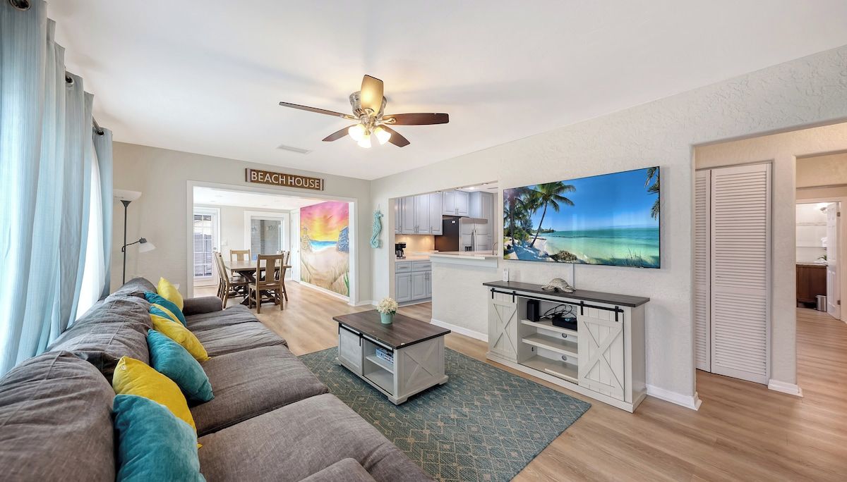 A living room with a sofa, a coffee table, and a painting of a beach scene.