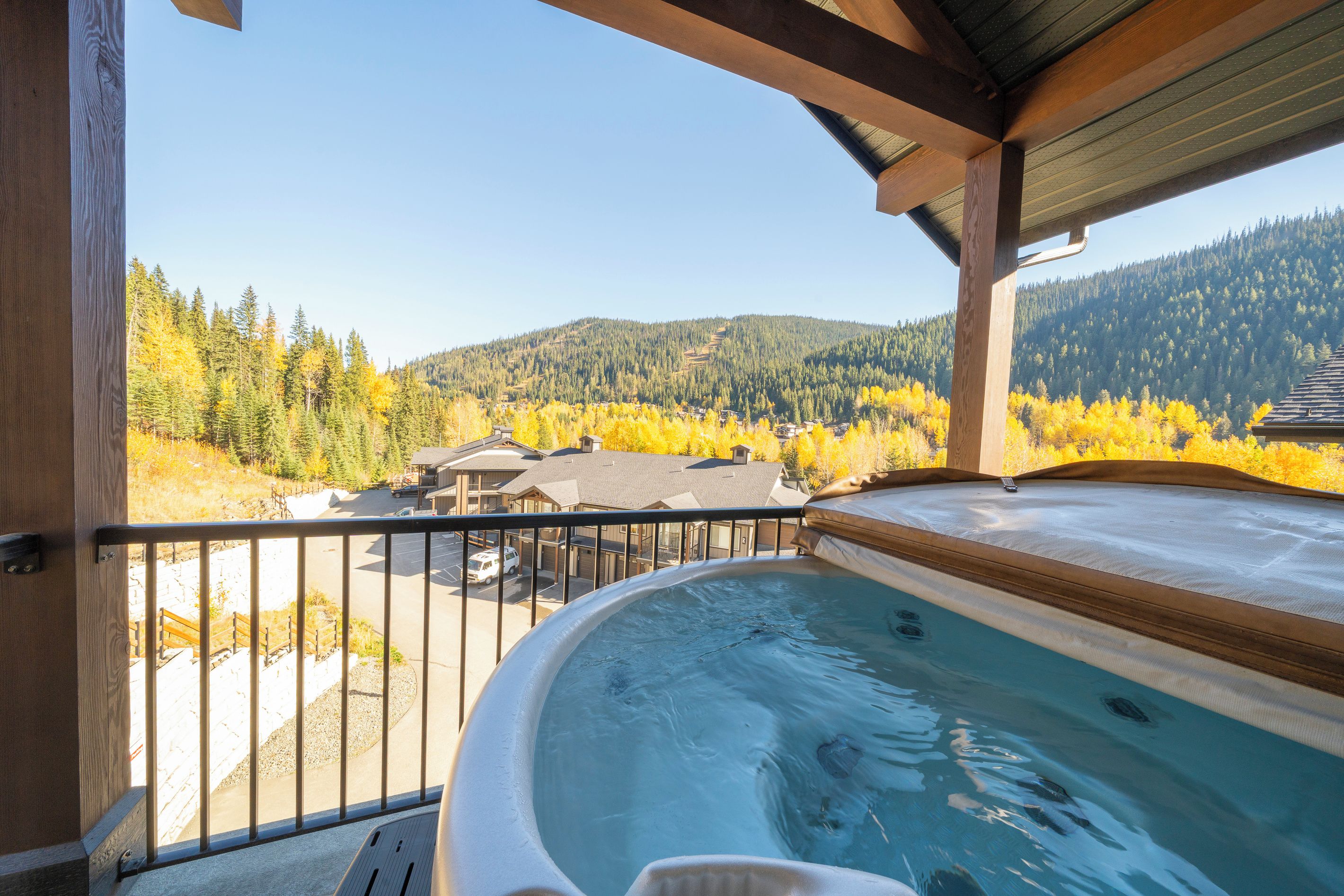 A hot tub on a balcony with a view of a forested mountain and a residential area.