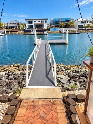 A dock leading to a marina with houses in the background.