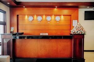 A reception desk with a wooden finish, multiple clocks, and a reception sign.
