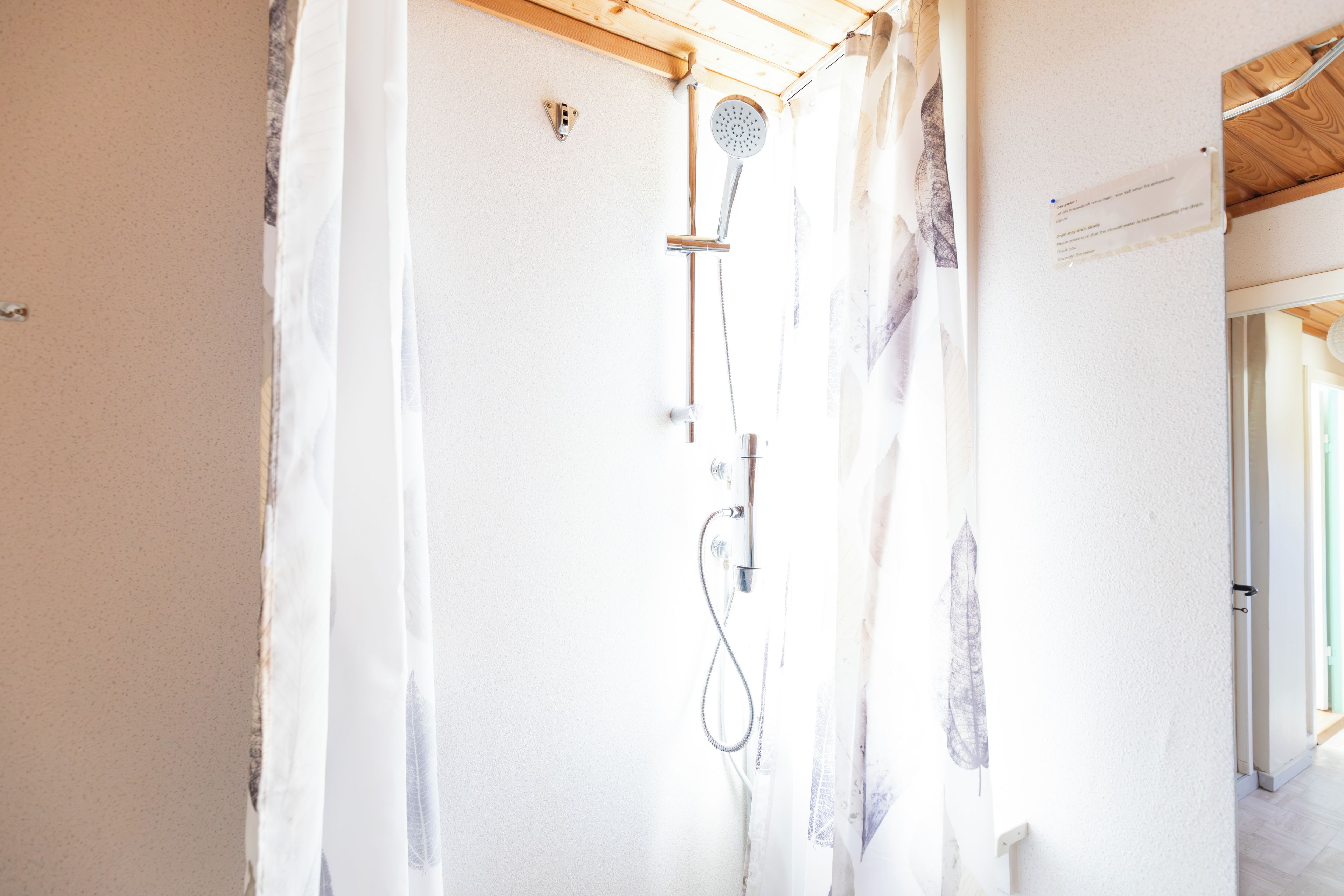 A shower with a handheld showerhead and a wall-mounted faucet.