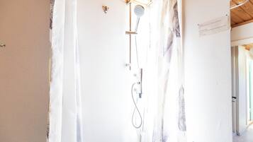 A shower with a handheld showerhead and a wall-mounted faucet.
