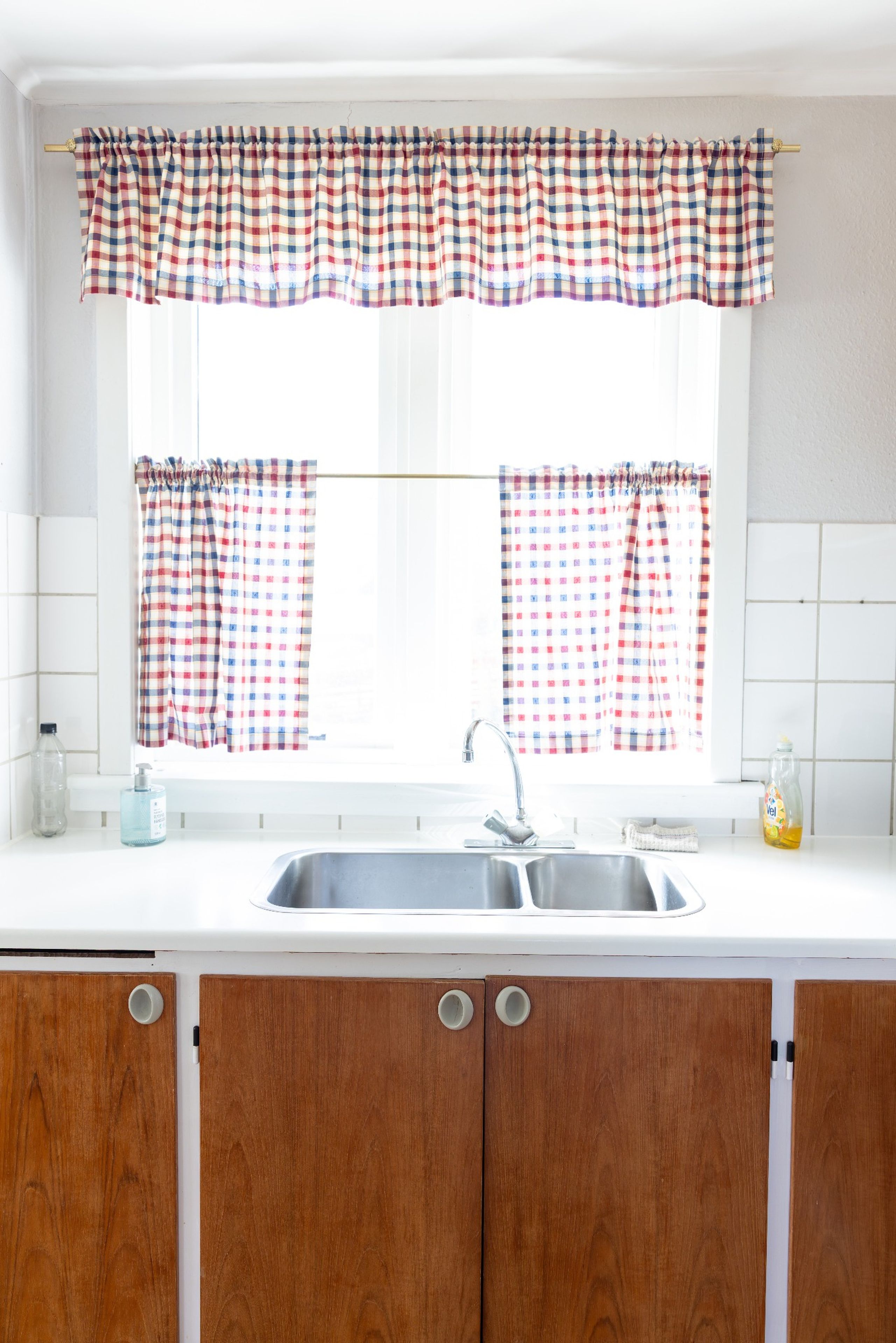 A kitchen with a window, a sink, and wooden cabinets.