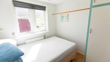 Een slaapkamer met een enkel bed, een raam met uitzicht, een radiator en een kledingkast.