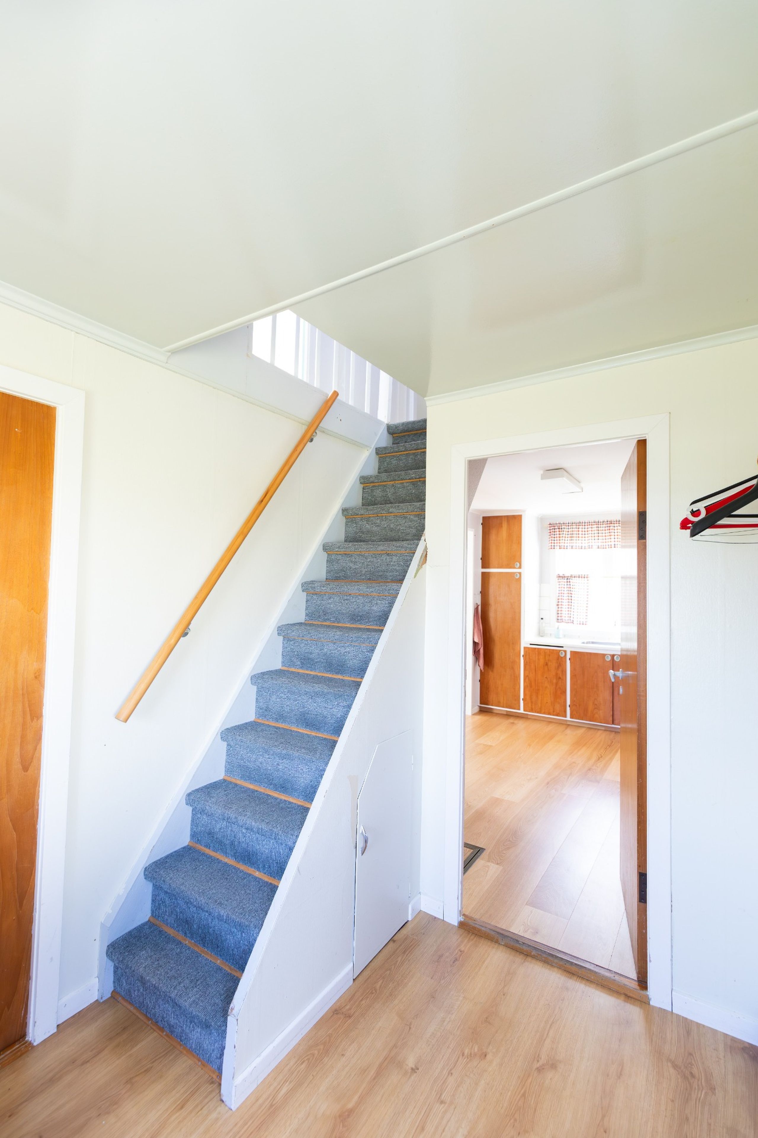 A staircase with blue carpet leading to a kitchen area.