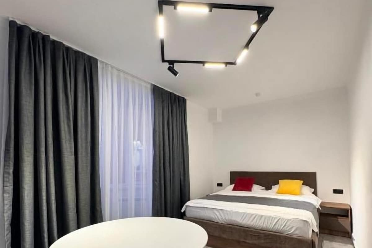 Et moderne hotelværelse med et rundt bord, en seng med trægavl og en lampe i loftet.