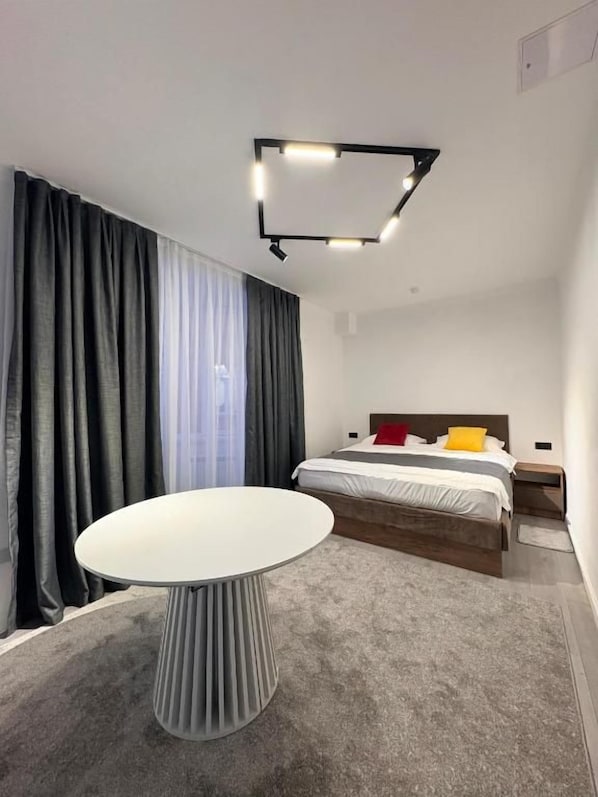 Et moderne hotelværelse med et rundt bord, en seng med trægavl og en lampe i loftet.