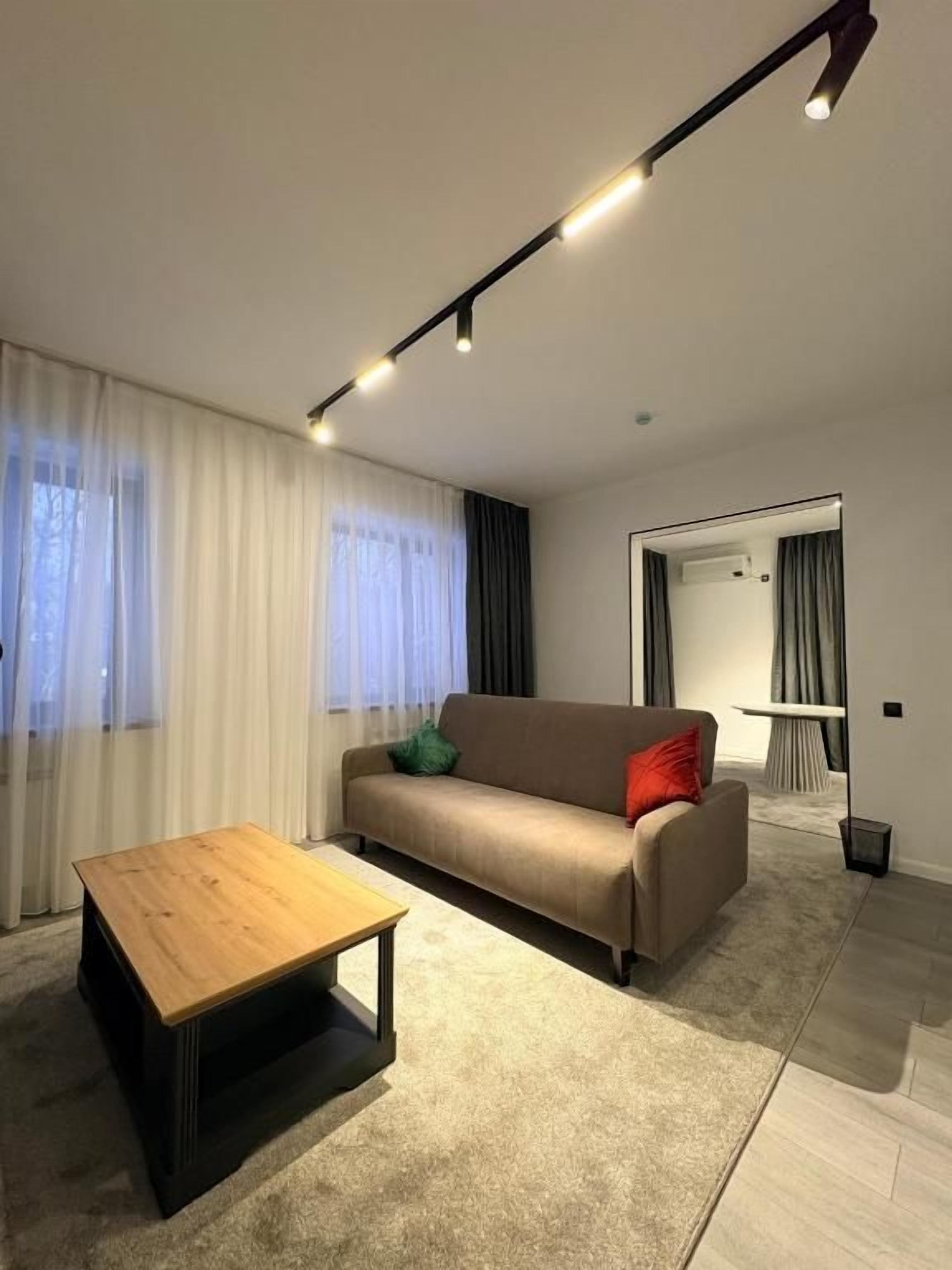 Un saló modern amb un sofà, una taula de centre i una zona de menjador amb taula i cadires.