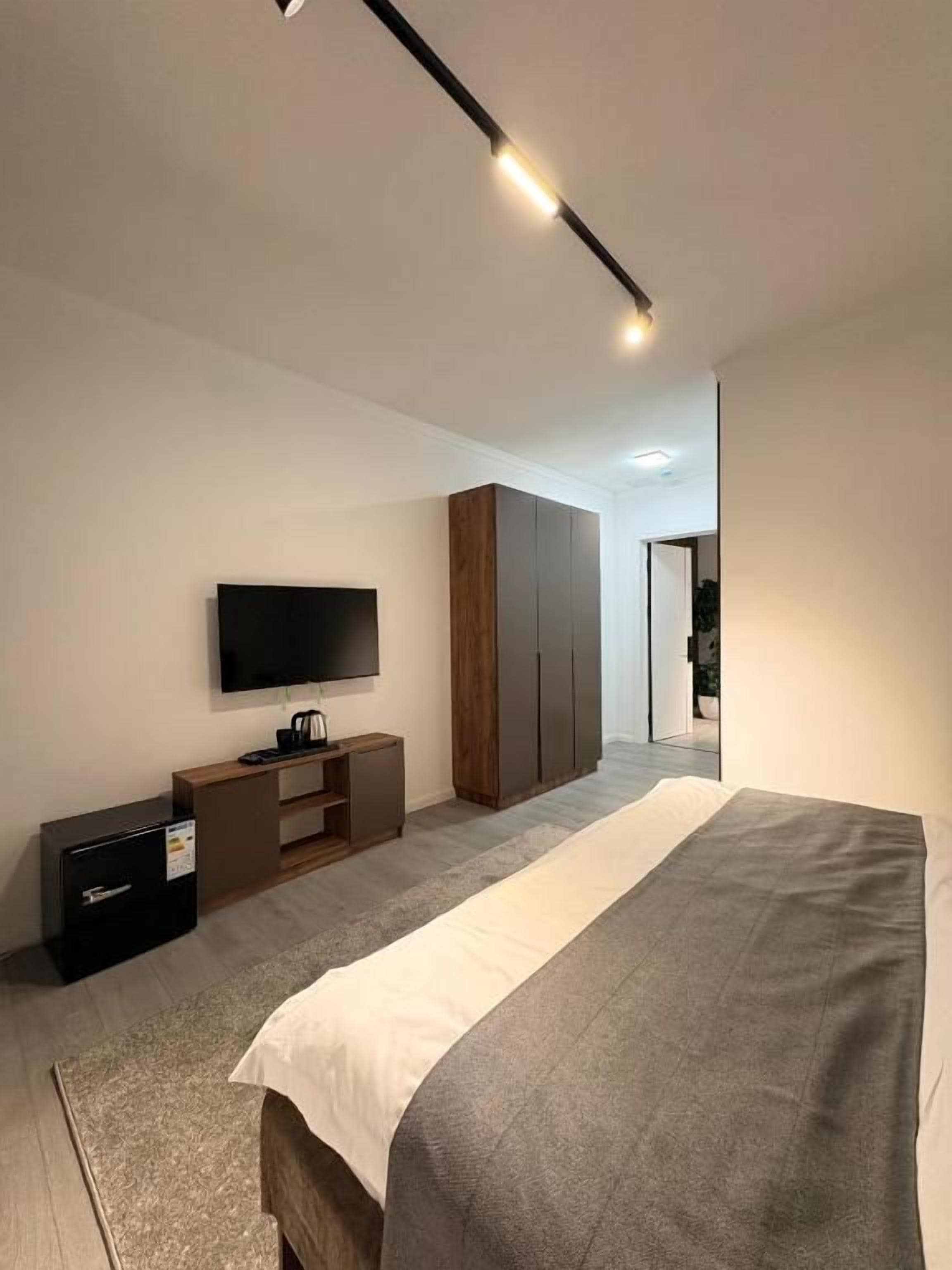 Habitació d'hotel moderna amb llit, televisió de pantalla plana, armari i escriptori amb ordinador.