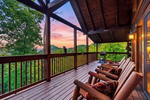 Um deck de madeira com vista para uma floresta e montanhas.