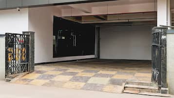 Entrada a un aparcamiento con suelo a cuadros, puertas metálicas y una puerta visible.