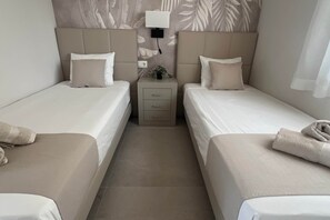 A hotel room with two single beds, a bedside table with a lamp, and a wall-mounted power outlet. - Villa Olivia - Mar Menor Golf Resort (Torre-Pacheco)