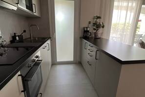A modern kitchen with a black countertop, stainless steel appliances, and a view to the outside. - Villa Olivia - Mar Menor Golf Resort (Torre-Pacheco)