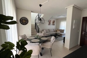 Un espace de vie moderne comprenant un coin repas, un escalier et un ensemble de canapés.